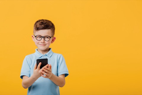 A boy in glasses smiling at a mobile phone